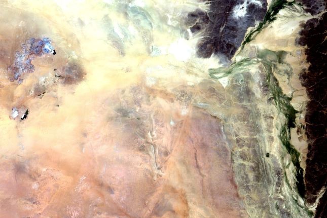 Uranium mines appear in blue, at left; dark spot on right is the Nigerien urban area of Arlit, desert sands in yellow and orange. (Coordenação-Geral de Observação da Terra/INPE, Flickr, Wikiedia Commons, CC BY-SA 2.0)